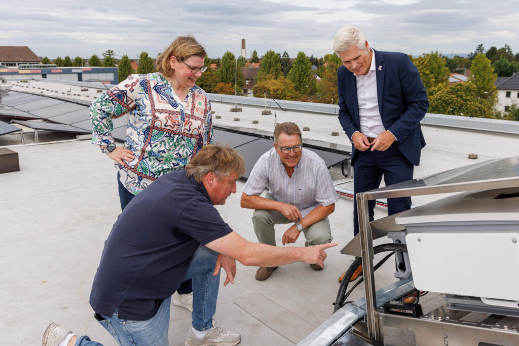 Oberbürgermeister Matthias Steffan und die beiden Vorstände der Bürgerenergiegenossenschaft Kurpfalz (BEG), Martina Braun und Jürgen Schmitt auf dem Dach des Hebel-Gymnasiums